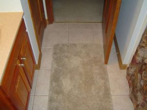 Bathroom ceramic tile floor with floor rugs.