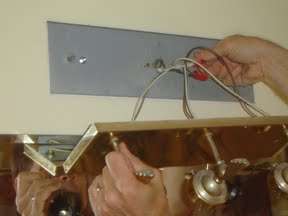 Removing bathroom light fixture from the wall.